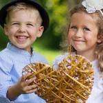 Two laughing kids holding wicker heart
